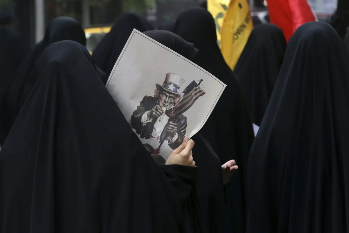 A female Iranian demonstrator holds a poster showing a caricature of Uncle Sam during an annual anti-U.S. rally in front of the former U.S. Embassy in Tehran, marking 36th anniversary of the seizure of the embassy by militant Iranian students, Iran, Wednesday, Oct. 4, 2015. The annual state-organized rally Wednesday drawing greater attention this year, as Iranian hardliners are intensifying a campaign to undermine President Hassan Rouhani's outreach to the West following a landmark nuclear deal reached with world powers in July. (AP Photo/Vahid Salemi)