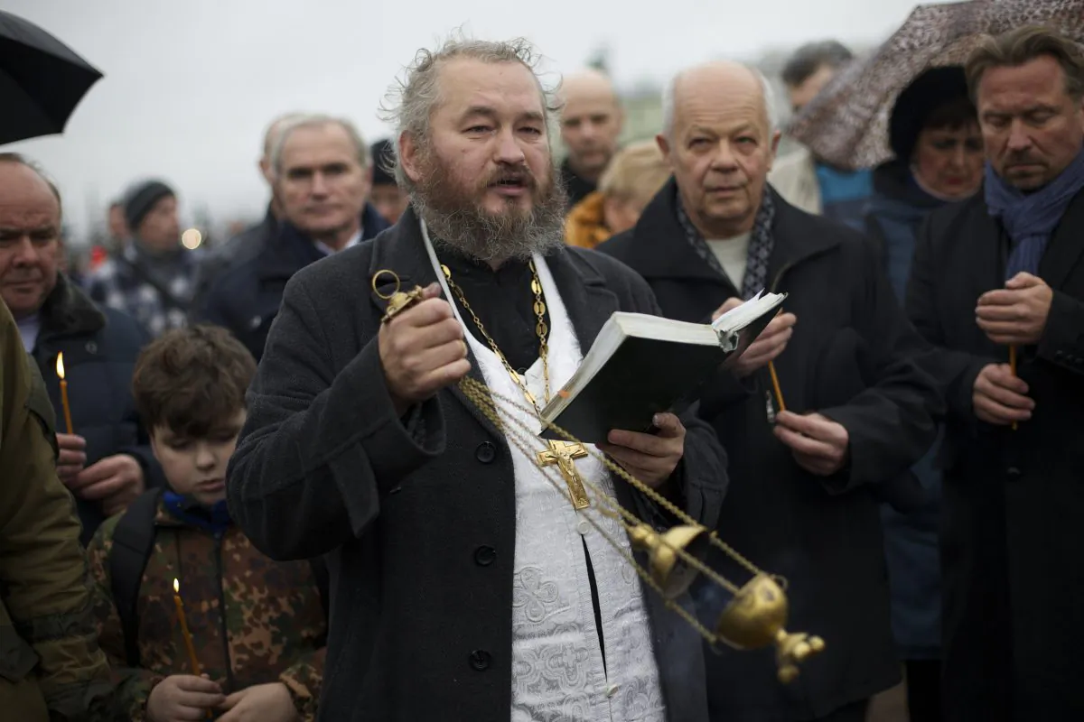 An Orthodox priest conducts an improvised religious service in memory of the plane crash victims in St. Petersburg, Russia, on Wednesday, Nov. 4, 2015. (AP Photo/Ivan Sekretarev)