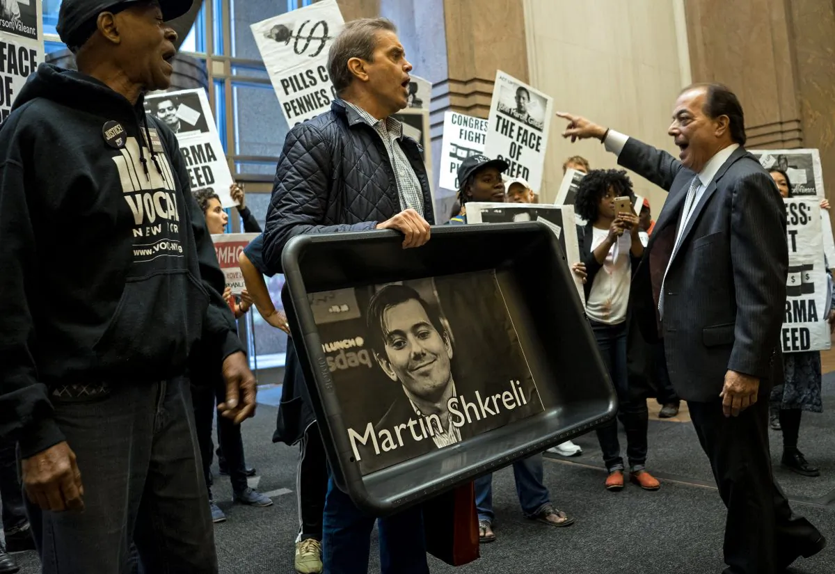 AIDS activists and others, carrying an image of Turing Pharmaceuticals CEO Martin Shkreli in a makeshift cat litter pan, are asked to leave the lobby of 1177 6th Ave. in New York, during a protest highlighting pharmaceutical drug pricing, on Oct. 1, 2015. (AP Photo/Craig Ruttle)