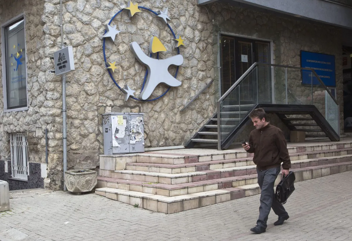 A Kosovar checks his mobile phone as he walks past EU Information and Cultural Office in Kosovo's capital Pristina Tuesday, Nov. 27, 2015. (AP Photo/Visar Kryeziu)