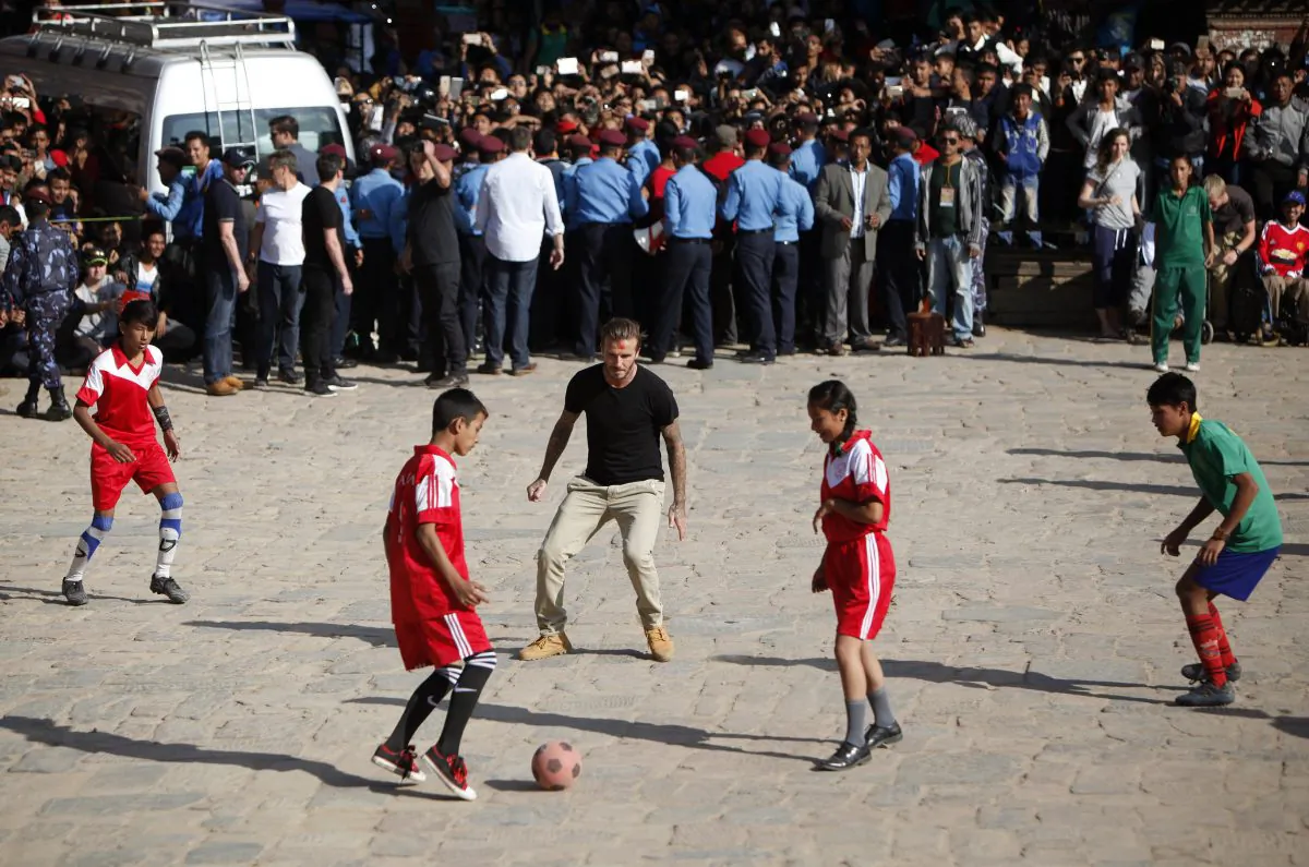 Former soccer player David Beckham plays football with Nepalese students in Bhaktapur, Nepal, Friday, Nov. 6, 2015. Beckham, who is in Nepal filming a documentary for UNICEF, visited the Shree Padma Higher Secondary School, where classes are being held in temporary sheds. He later played soccer with the children at an open courtyard, cheered on by hundreds of fans. (AP Photo/Niranjan Shrestha)