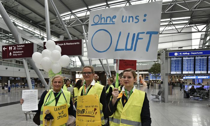 Lufthansa flight attendants protest at the airport in Duesseldorf, Germany, Friday, Nov. 5, 2015. The poster reads "without us - 0 air." Germany's flagship airline, Lufthansa, canceled 290 flights on Friday as cabin crew workers went on strike at Frankfurt and Duesseldorf airports. The carrier said the cancellations included 23 long-haul flights, and that overall some 37,500 passengers were affected. (AP Photo/Martin Meissner)