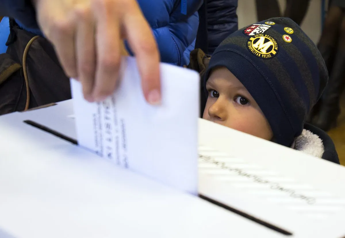 A child looks at a ballot being cast at a polling station in Zagreb, Croatia, Sunday, Nov. 8, 2015. Croatia's ruling center-left coalition faces a strong challenge from a conservative opposition in the Balkan country's first parliamentary election since joining the European Union in 2013. (AP Photo/Darko Bandic)