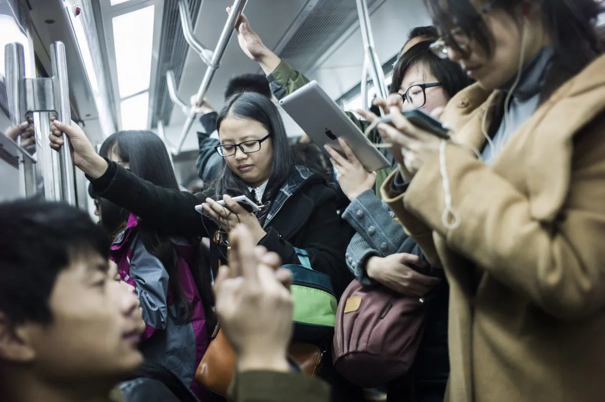 Commuters watch movies on their mobile phones and tablets in a metro car in Beijing on Nov. 17, 2014. (Fred Dufour/AFP/Getty Images)