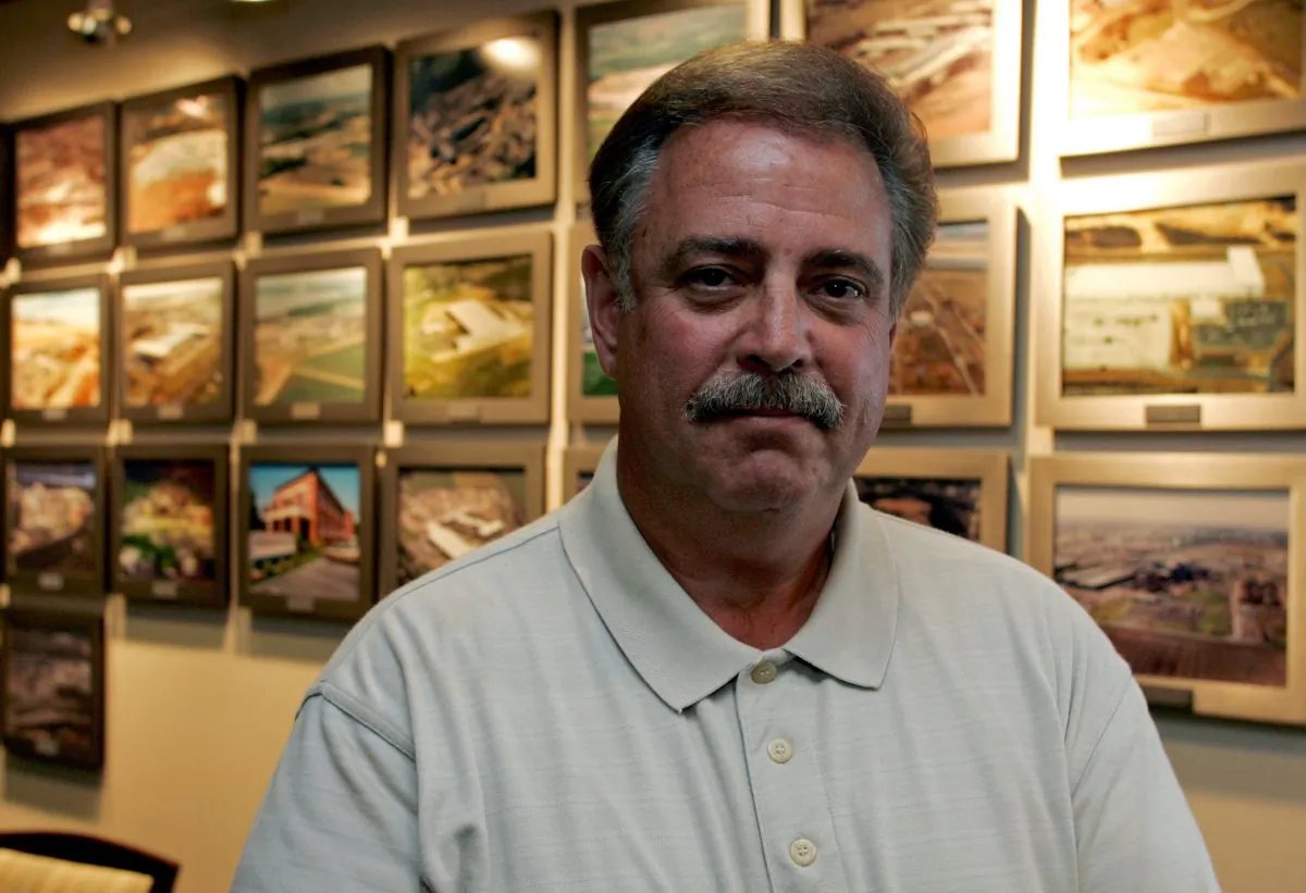 Dan DiMicco, chairman emeritus of Nucor Corp., stands near photos of the company's steel plants at the company's headquarters in Charlotte, N.C., on July 18, 2006. (AP Photo/Chuck Burton)