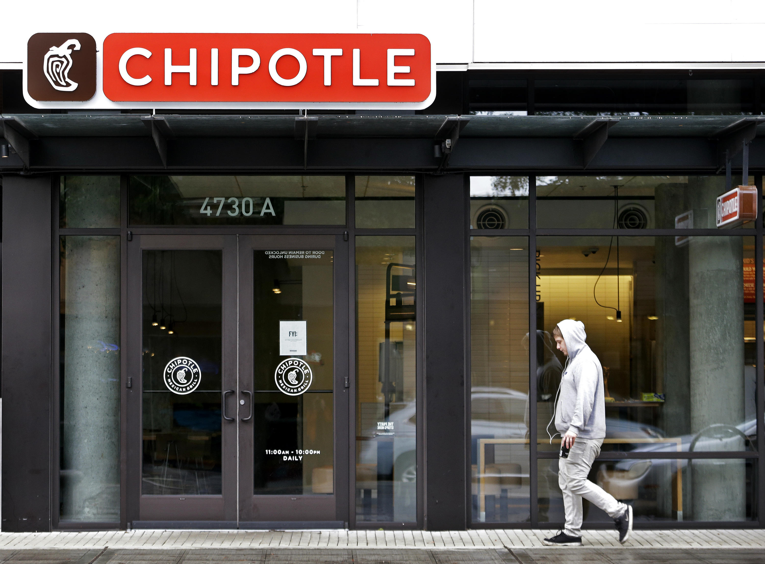 A pedestrian walks past a closed Chipotle restaurant in Seattle on Nov. 2, 2015. Washington state health officials say they have found no source for the E. coli outbreak related to Chipotle and the chain's Pacific Northwest restaurants could reopen later this week. Washington state epidemiologist Dr. Scott Lindquist says all the tests of food from Chipotle stores in Washington and Oregon came back negative for E. coli. (AP Photo/Elaine Thompson)