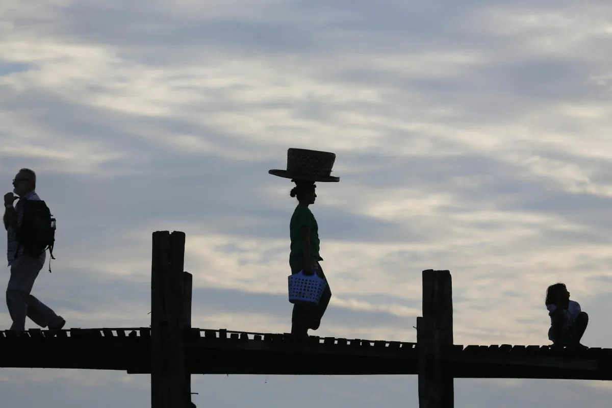 A street vender (C) walks on the historic U Bein Bridge near Amarapura, in Mandalay, Burma, on Nov. 10, 2015. Burma was trapped in a post-election limbo Tuesday with official results barely trickling in, although opposition leader Aung San Suu Kyi's party claimed a victory massive enough to give it the presidency and loosen the military's grip on the country. (AP Photo/Hkun Lat)
