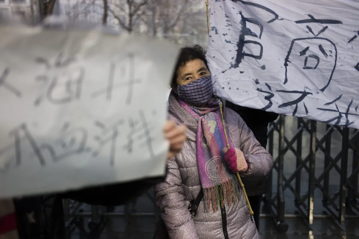 A woman holds up a banner as a group protests about alleged local government wrongdoing and unpaid wages outside the Langfang Court on Dec. 10, 2014. (Fred Dufour/AFP/Getty Images)