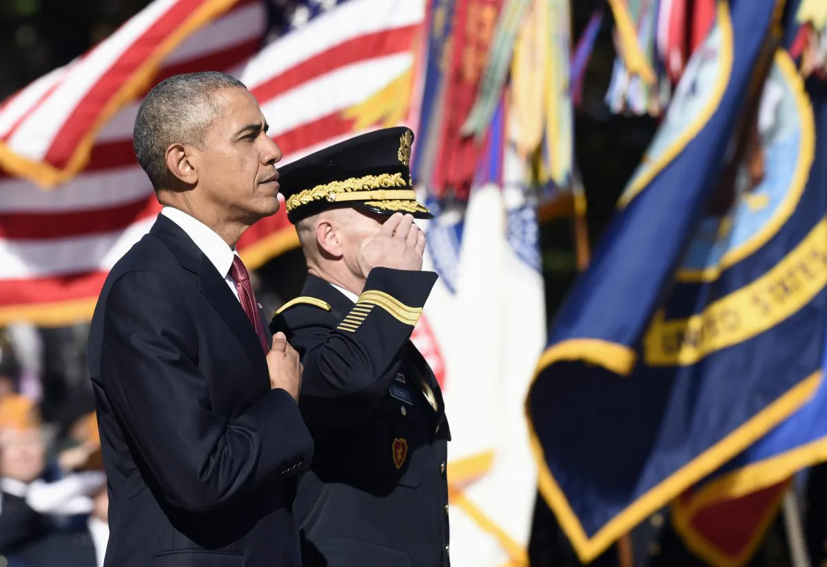 President Barack Obama, accompanied by Maj. Gen. Bradley A. Becker, Commanding General, U.S Army Military District of Washington, listens to the National Anthem after laying a wreath at the Tomb of the Unknowns, Wednesday, Nov. 11, at Arlington National Cemetery in Arlington, Va., during Veterans Day ceremonies. (AP Photo/Susan Walsh)
