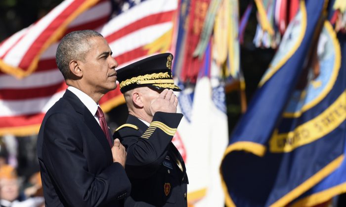 President Barack Obama, accompanied by Maj. Gen. Bradley A. Becker, Commanding General, U.S Army Military District of Washington, listens to the National Anthem after laying a wreath at the Tomb of the Unknowns, Wednesday, Nov. 11, at Arlington National Cemetery in Arlington, Va., during Veterans Day ceremonies. (AP Photo/Susan Walsh)