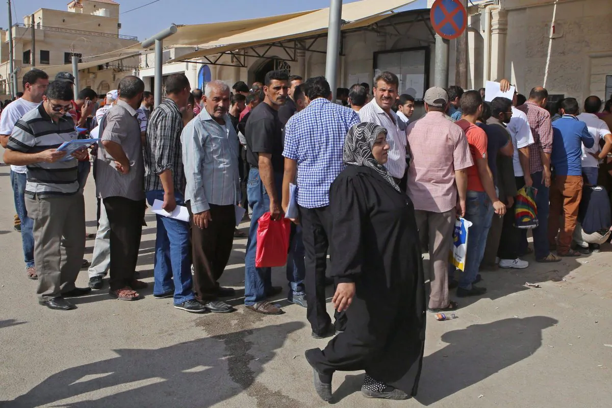 Syrian refugees gather outside their embassy waiting to apply for passports or renew their old passports, in Amman, Jordan, Sept. 15, 2015. (The Canadian Press/ AP/Raad Adayleh)