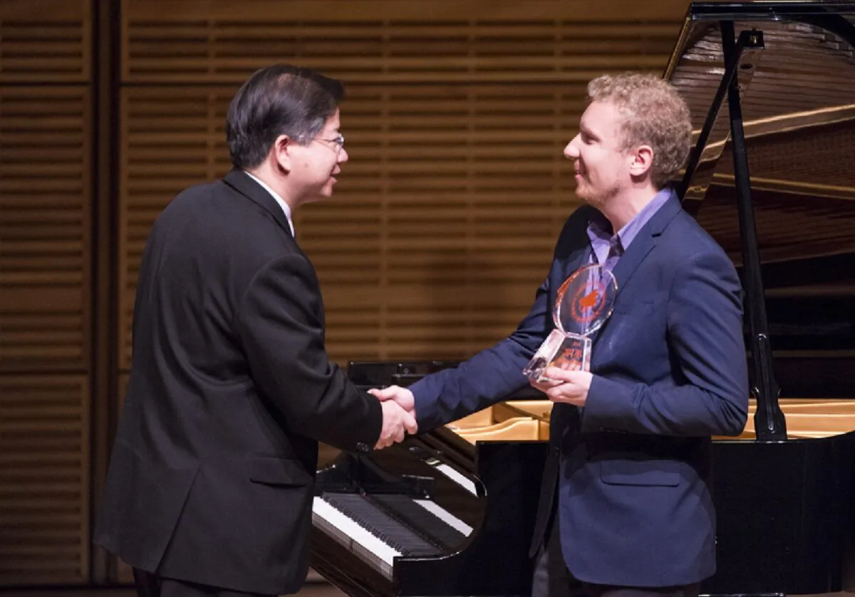 Pianist Anton Smirnoff receives the bronze award from NTDTV president Tang Zhong at the conclusion of the NTD Television's 2014 International Piano Competition at Carnegie Hall on Oct. 5, 2014. (Dai Bing/Epoch Times)
