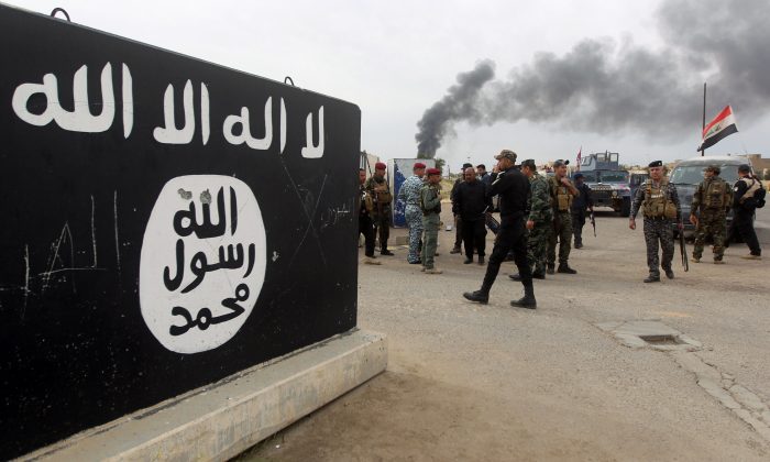 Iraqi security forces and Shiite fighters gather next to a mural showing the emblem of ISIS on April 1 in Tikrit, after retaking the city from ISIS. (Ahmad Al-Rubaye/AFP/Getty Images)