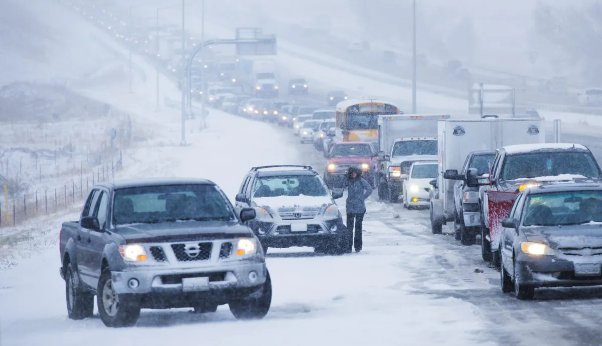 Brittany Tappen stands next to her vehicle, one of several that were stranded by ice and snow on the northbound off ramp from I-25 to Baptist Road during the morning commute north of Colorado Springs, Colo., on Nov. 11, 2015. The storm system that dropped a foot of snow in the Rockies was making travel hazardous as it headed east on Wednesday, menacing the Plains with heavy snow and threatening turbulent weather, even tornadoes, in parts of the Midwest. (Mark Reis/The Gazette via AP) 