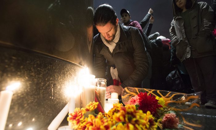 People light candles at a vigil outside the French consulate in Montreal, Friday, Nov. 13, 2015. Canadian Prime Minister Justin Trudeau offered "all of Canada's support" to France on Friday night in the wake of "deeply worrying" terrorist attacks in Paris. (Graham Hughes/The Canadian Press via AP)