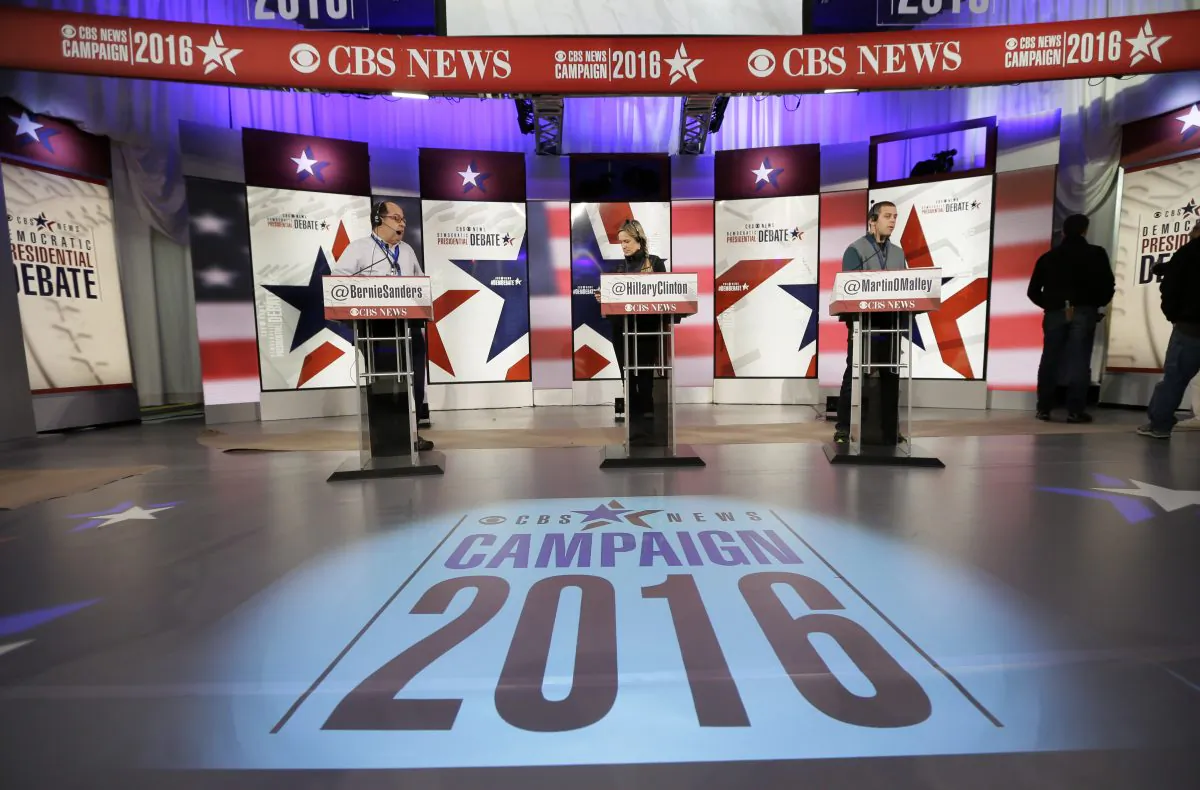 Workers stand at the podiums on stage during final preparations for Saturday night's Democratic presidential debate between Sen. Bernie Sanders (I-Vt.), Hillary Rodham Clinton and former Maryland Gov. Martin O'Malley, in Des Moines, Iowa, on Nov. 13, 2015. (AP Photo/Charlie Neibergall)