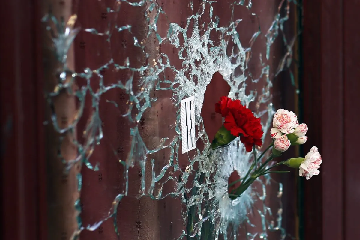 Flowers are set in a window shattered by a bullet at the Carillon cafe in Paris, France, on Nov. 15, 2015, two days after over 120 people were killed  in a series of shooting and explosions, including suicide bombers. (AP Photo/Jerome Delay)