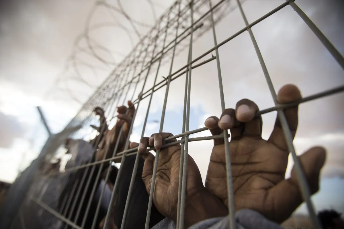 African asylum seekers, who entered Israel illegally via Egypt, lean at the fence of the Holot detention center in Israel's southern Negev Desert, on Feb. 17, 2014, as they join other migrants who came to protest outside the detention facility. (Jack Guez/AFP/Getty Images)