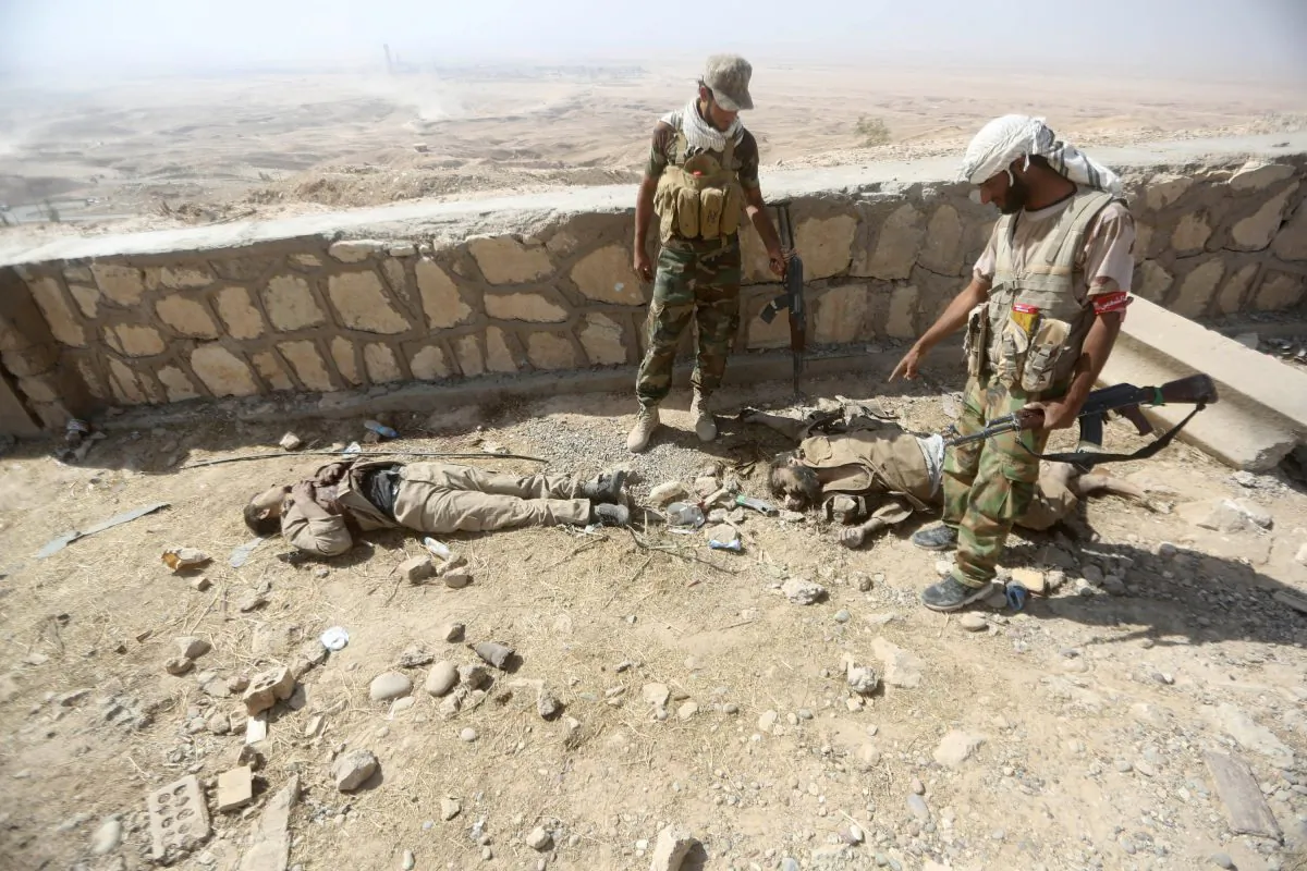 Iraqi Shiite fighters from the Popular Mobilization units, fighting alongside Iraqi forces, look at bodies of Islamic State (ISIS) fighters during a military operation against ISIS jihadists in the Makhoul mountains, north of Baiji, on Oct. 17, 2015. After recapturing parts of Baiji and the huge nearby refinery complex from ISIS, security and allied paramilitary forces thrust further northward up the main highway leading to Mosul. (Ahmad al-Rubaye/AFP/Getty Images)