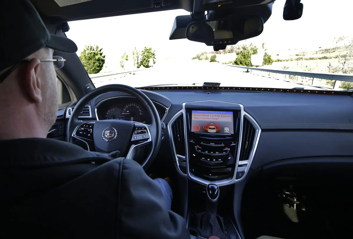 Virginia Tech Center for Technology Development Program Administration Specialist Greg Brown sits behind the wheel of a driverless car during a test ride showing the alert system handing over automation to the driver while driving on a local Blacksburg, Va., on Nov. 13, 2015. (Justin Fine/Virginia Tech via AP)