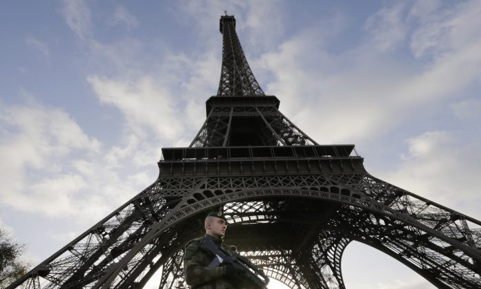 A French soldier stands alert at the Eiffel Tower which remained closed on the first of three days of national mourning in Paris, Sunday, Nov. 15, 2015. Thousands of French troops deployed around Paris on Sunday and tourist sites stood shuttered in one of the most visited cities on Earth while investigators questioned the relatives of a suspected suicide bomber involved in the country's deadliest violence since World War II. (AP Photo/Amr Nabil)