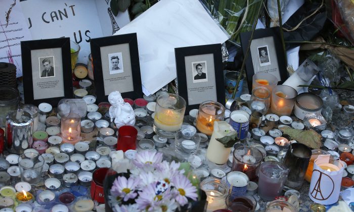 Pictures of victims are placed behind candles outside the Bataclan concert hall in Paris, Sunday, Nov. 15, 2015. (AP Photo/Christoph Ena)
