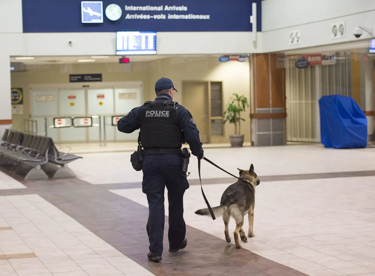 A police officer and a dog walk in the terminal at Halifax Stanfield International Airport after an Air France plane was diverted to the airport near Halifax, Nova Scotia, Wednesday, Nov. 18, 2015. (Andrew Vaughan/The Canadian Press via AP)