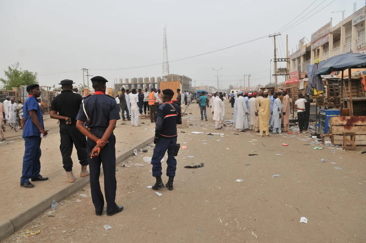 Security officers stand guard at the scene of an explosion at a mobile phone market in Kano, Nigeria, on Wednesday, Nov. 18, 2015. The suicide bomber exploded as truckers were tucking into dinner at the bustling marketplace where vendors urged them to buy sugar cane. At least 34 people were killed and another 80 wounded in Yola, a town packed with refugees from Nigeria's Islamic uprising, emergency officials said Wednesday. Later Wednesday, two more suicide bombers killed at least 15 people in the northern city of Kano and injured 53, according to police. (AP Photo/Muhammed Giginyu)