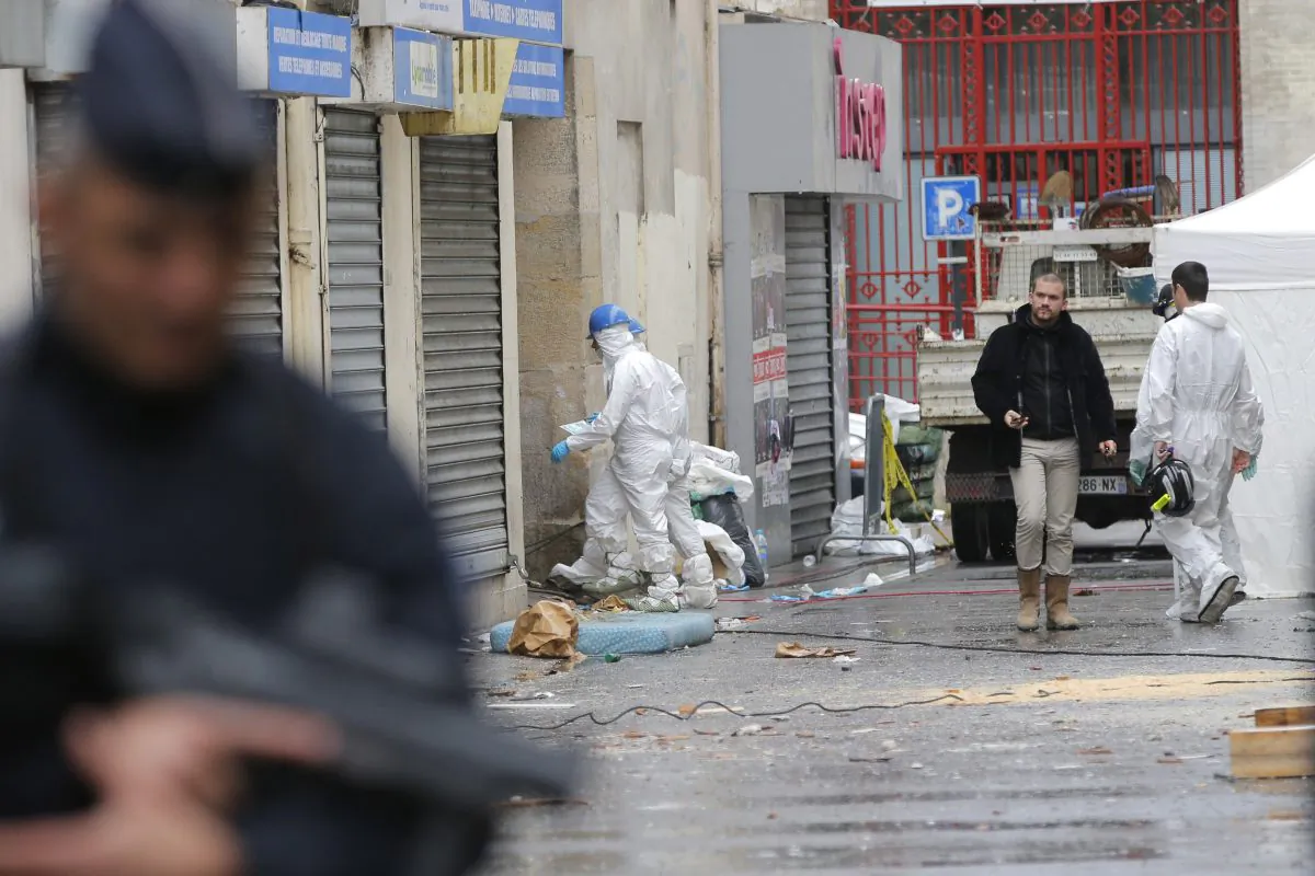 Investigating police officers enter the building of Wednesday's raid on an apartment in Paris suburb Saint-Denis, Thursday Nov.19, 2015. (AP Photo/Christophe Ena)