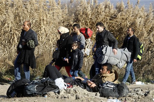 Migrants and refugees walk towards the border with Serbia, while other migrants, who were not allowed to cross into Serbia, lie on the ground awaiting for a solution, near the village of Tabanovce, in northern Macedonia, Thursday, Nov. 19, 2015. (AP Photo/Boris Grdanoski)