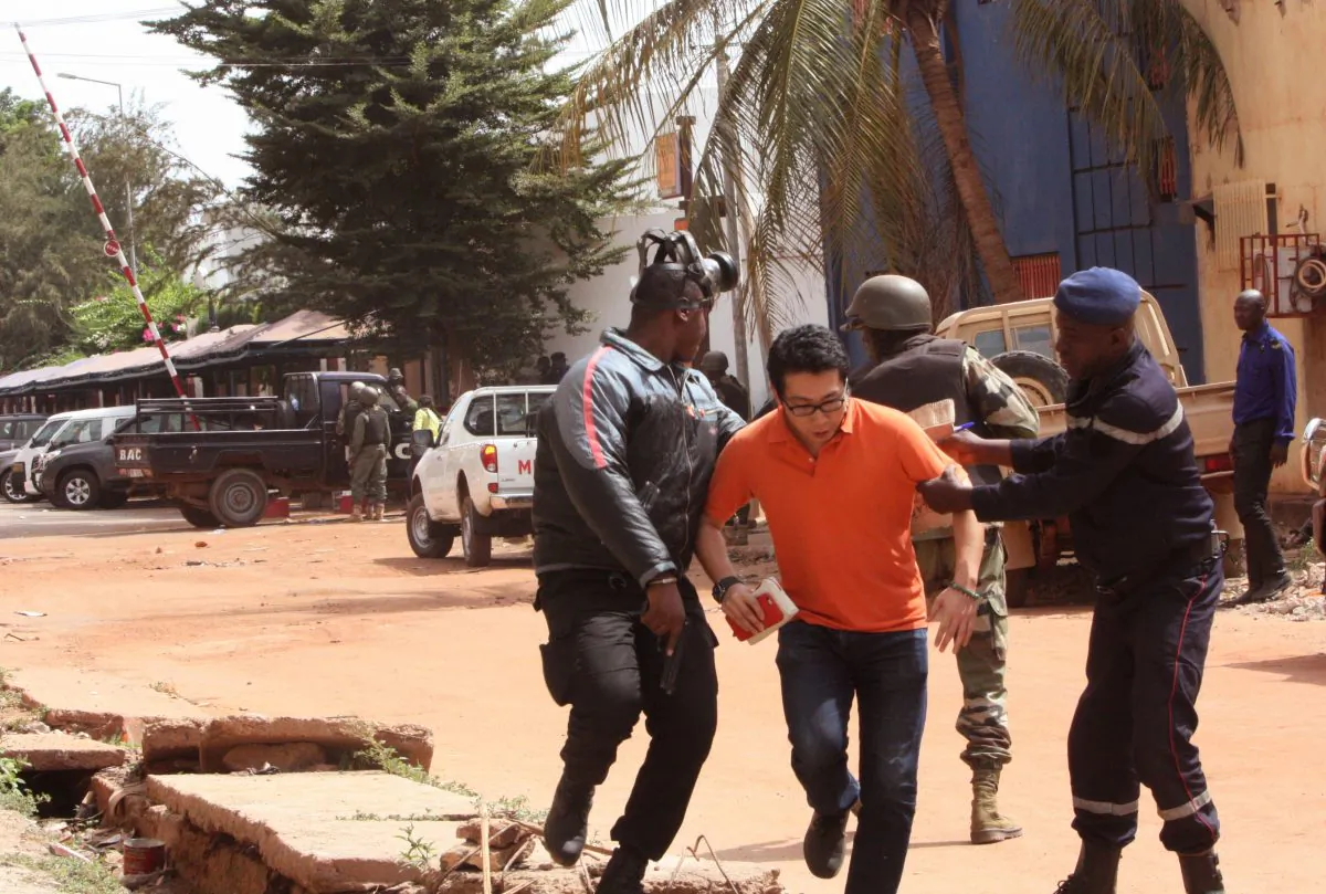 Mali trooper assist a hostage, centre, to leave the scene, from the Radisson Blu hotel to safety after gunmen attacked the hotel in Bamako, Mali, Friday, Nov. 20, 2015. Islamic extremists armed with guns and throwing grenades stormed the Radisson Blu hotel in Mali's capital Friday morning, killing at least three people and initially taking numerous hostages, authorities said. (AP Photo/Harouna Traore)