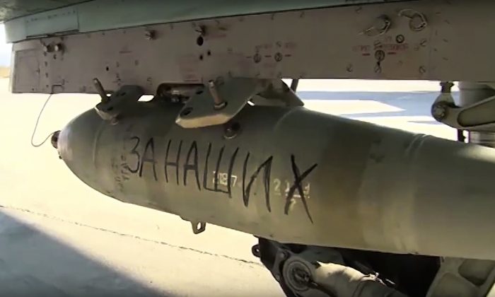 In this photo made from video released by Russian Defense Ministry official website on Friday, Nov. 20, 2015, "For Ours" is written on a bomb attached to a Russian war plane in preparation for a combat mission in Syria, according to information released by Russian Defense Ministry. (AP Photo/ Russian Defense Ministry Press Service)