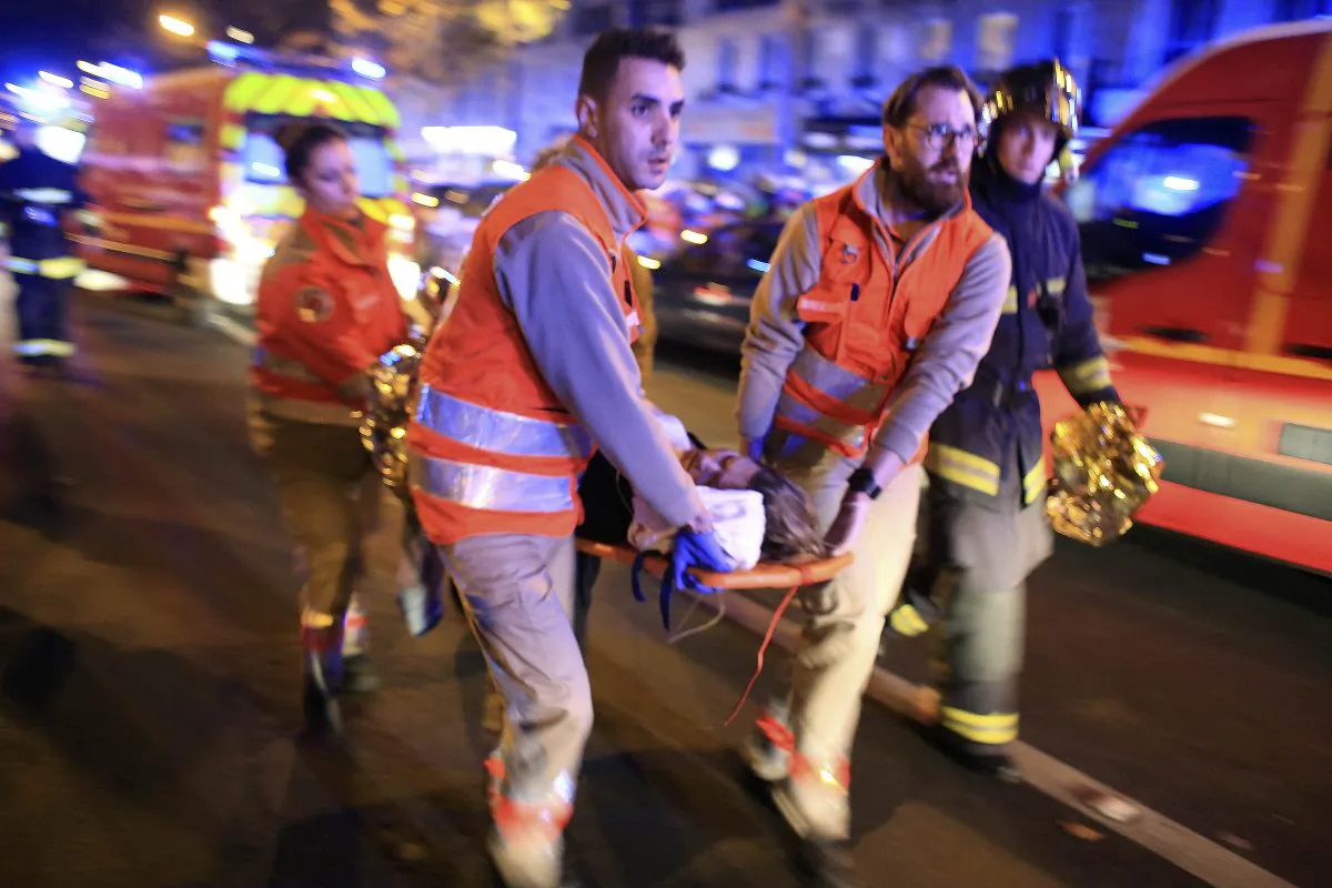 In this Nov.13, 2015 file photo, a woman is being evacuated from the Bataclan concert hall after a shooting in Paris. (AP Photo/Thibault Camus)