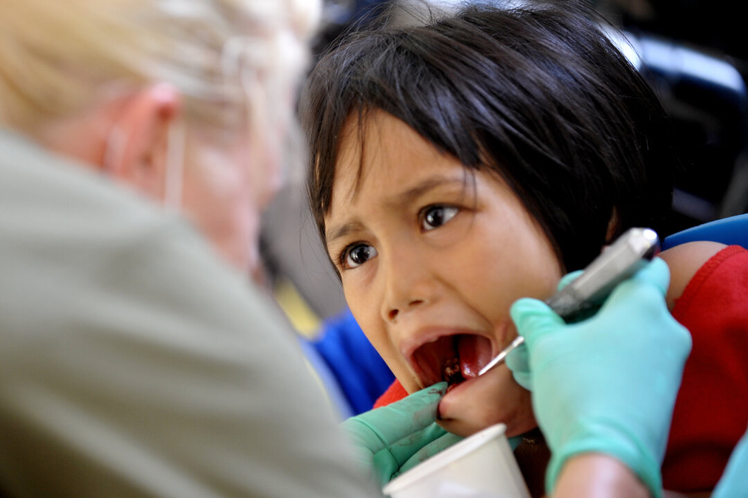 US Navy dentist Lieutenant Elisa Roth (L) looks at the teeth of a child in a file photo (Jay Directo/AFP via Getty Images)