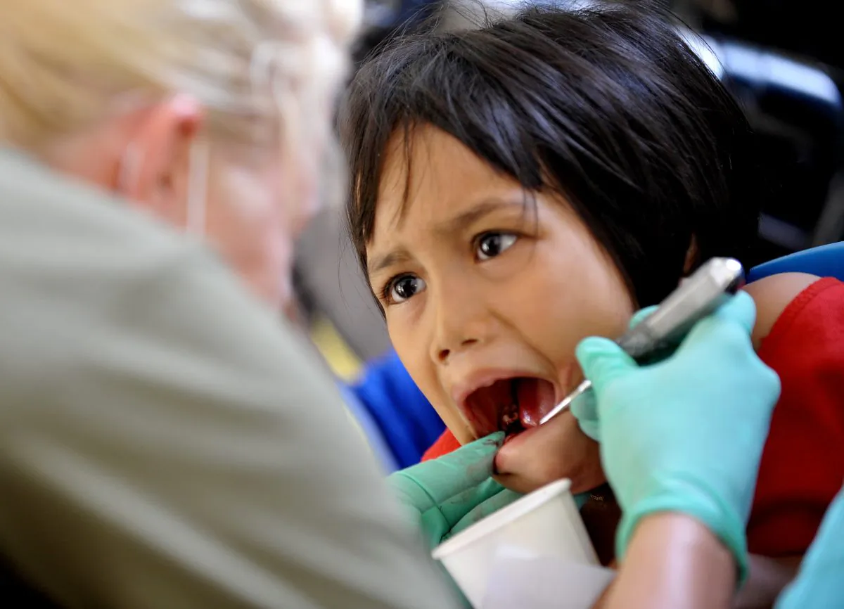 US Navy dentist Lieutenant Elisa Roth (L) looks at the teeth of a child in a file photo (Jay Directo/AFP via Getty Images)