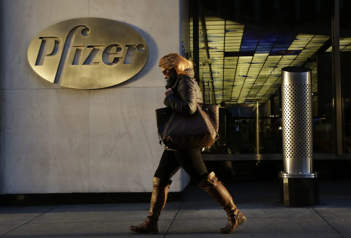 A woman passes Pfizer World Headquarters in New York on Monday, Nov. 23, 2015. Pfizer and Allergan will join in a $160 billion deal to create the world's largest drugmaker. (AP Photo/Mark Lennihan)