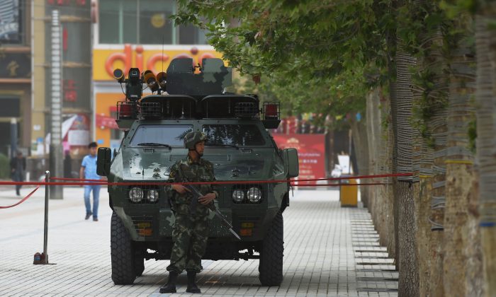 The undated photo shows a member of the Chinese paramilitary police in front of an armored vehicle in Hotan, Xinjiang region of China. The Chinese regime has deepened its suppression of the Uyghur ethnic group in the region. (Greg Baker/AFP/Getty Images)