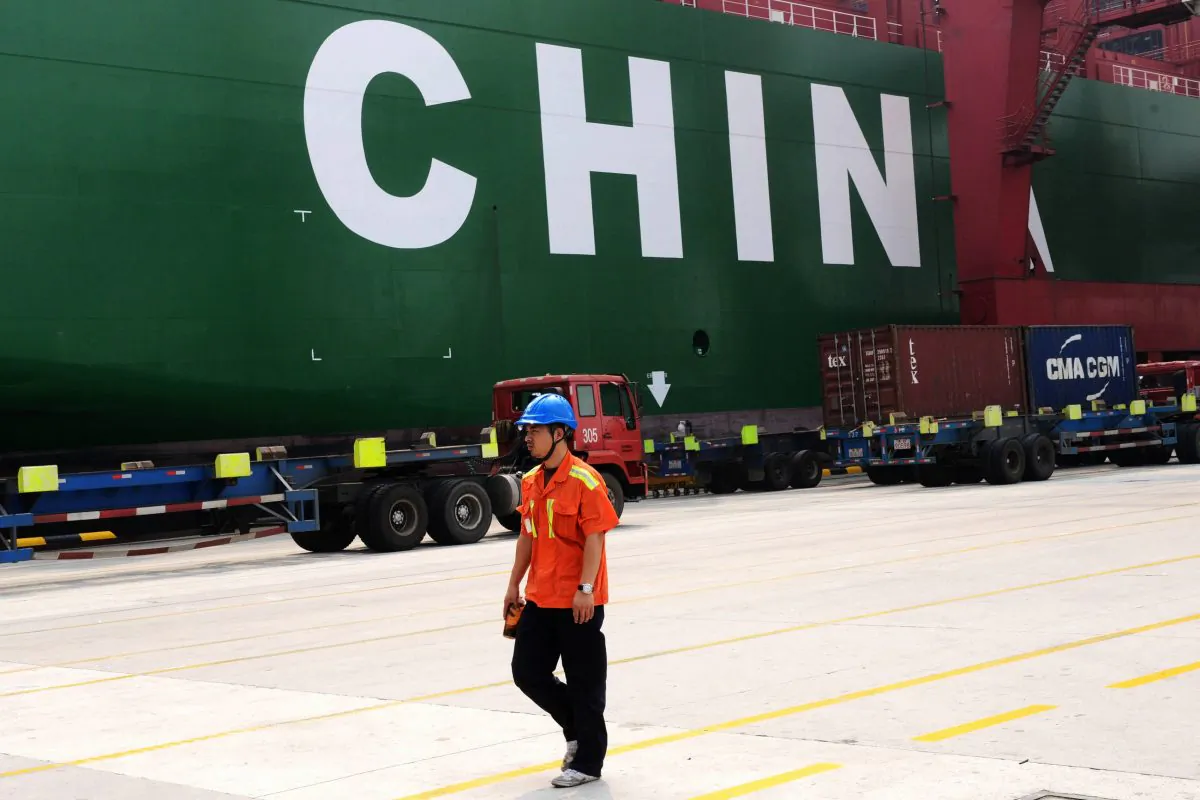 A worker walking past a cargo ship in Qingdao port, eastern China's Shandong province, on Oct. 13. (STR/AFP/Getty Images)