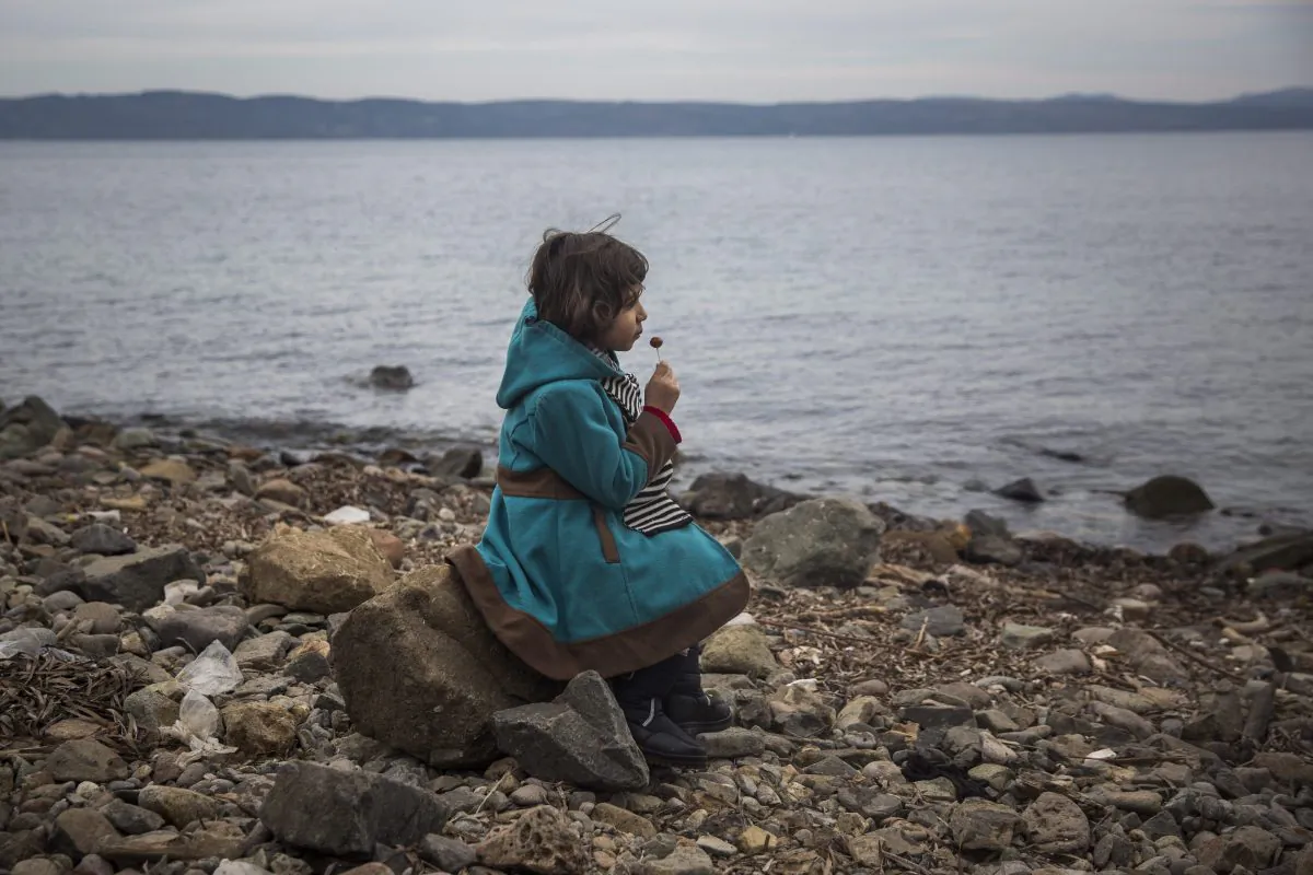 A Syrian girl eats a lollipop after her arrival on a small boat from the Turkish coast on the northeastern Greek island of Lesbos on Nov. 16, 2015. (AP Photo/Santi Palacios)