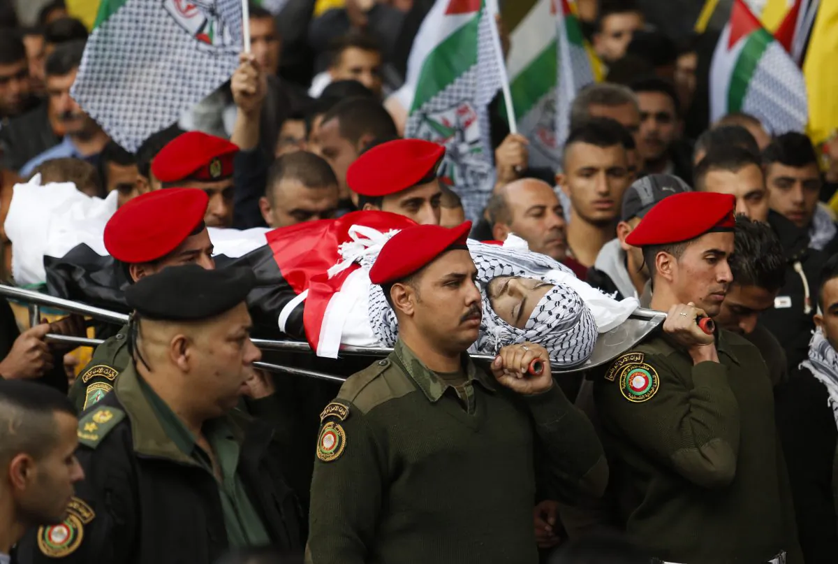 Palestinian security officers carry the body of 16-year-old Ibrahim Dawood during his funeral in the West Bank city of Ramallah, Thursday, Nov. 26, 2015. (AP Photo/Nasser Shiyoukhi)