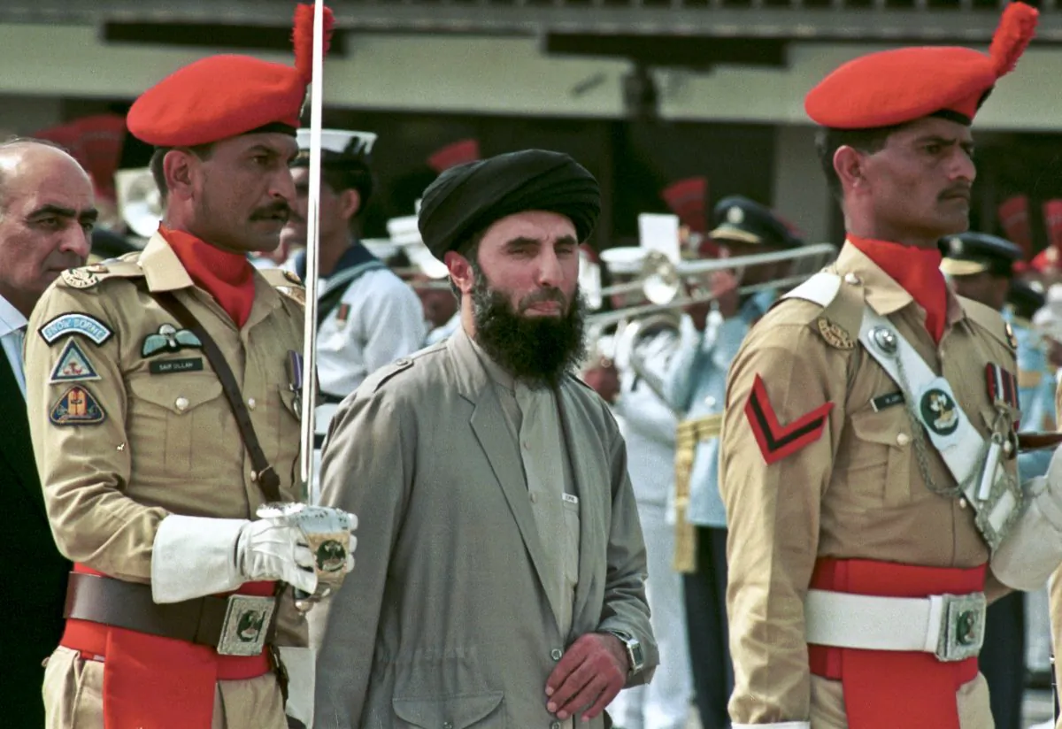 In this Wednesday, June 26, 1996 file photo, Gulbuddin  Hekmatyar, center, passes in front of an honor guard in the Afghan capital of Kabul, Afghanistan.  (AP Photo)