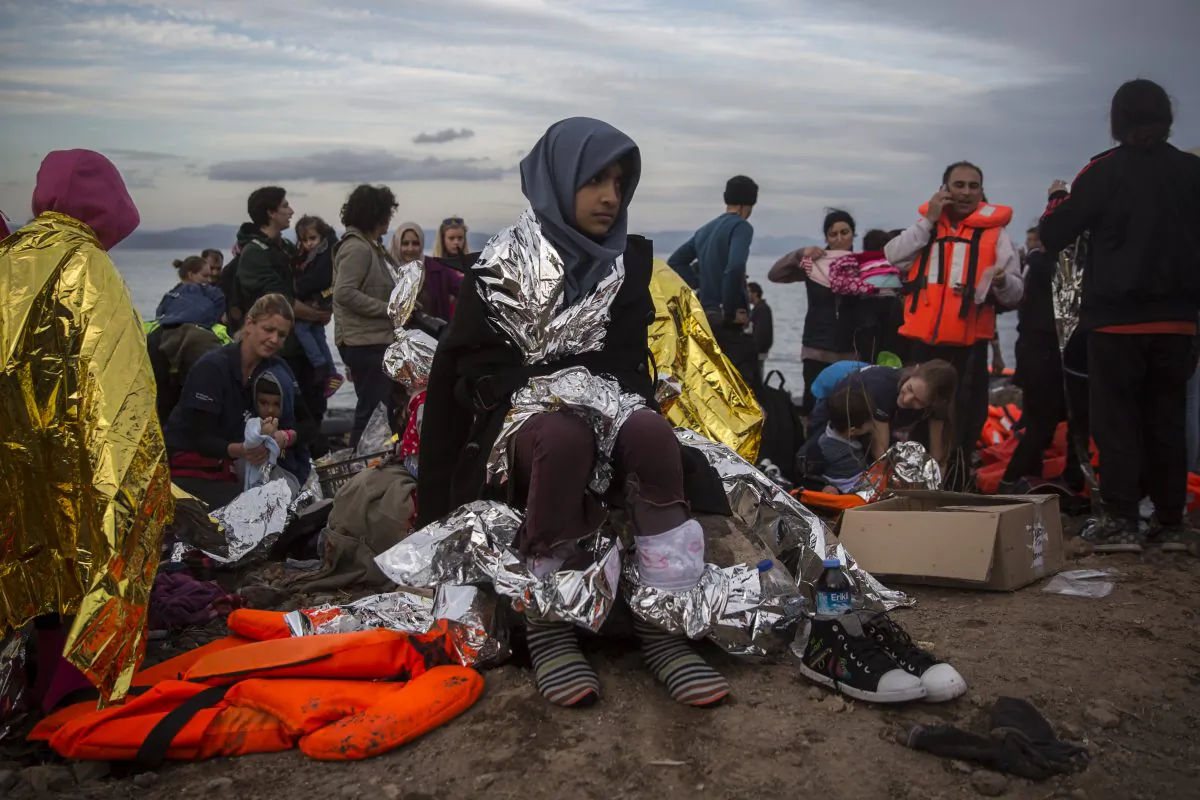 Refugees are helped by volunteers after crossing the Aegean sea on a dinghy from the Turkey's coast to the northeastern Greek island of Lesbos, on Tuesday, Nov. 24, 2015. Several European countries, including EU members Slovenia and Croatia and non-members Serbia and Macedonia, have declared they will only allow "war-zone refugees" from Afghanistan, Iraq and Syria to transit through their countries on their way to central and northern Europe. (AP Photo/Santi Palacios)