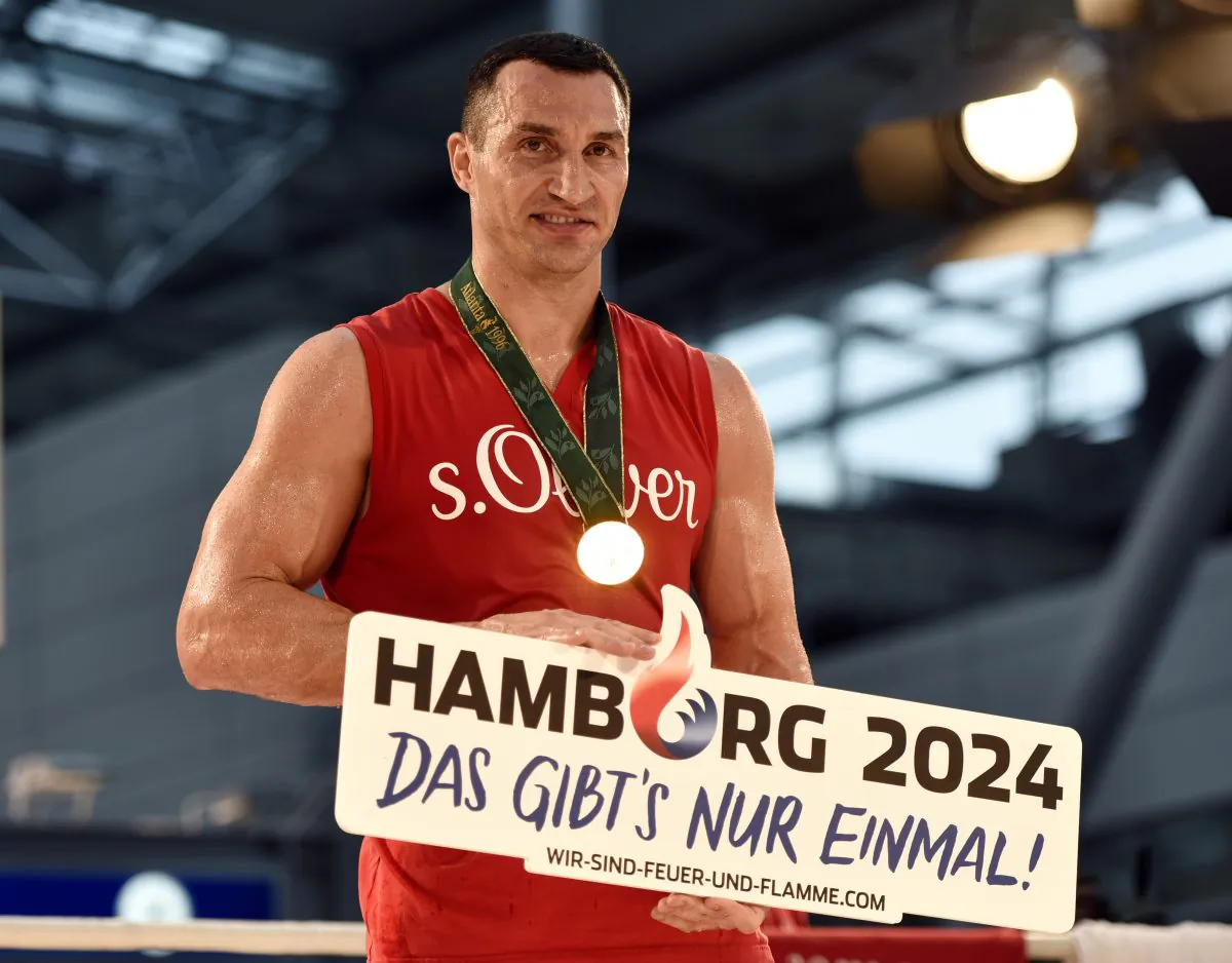 Ukrainian World boxing champion Wladimir Klitschko promotes Hamburg's bid for Olympic Games in 2024 during a public training session at the airport in Duesseldorf, Germany, prior his heavyweight boxing fight against challenger Tyson Fury from Britain, Wednesday, Nov. 25, 2015. The title bout will take place in Duesseldorf's  LTU arena on Saturday.  Poster reads: Hamburg 2024, and : This is unique'. (AP Photo/Martin Meissner)