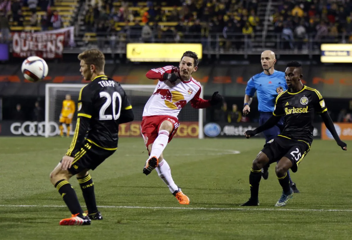 New York Red Bulls midfielder Sacha Kljestan (16), center, takes a shot between Columbus Crew midfielder Wil Trapp (20), left, and defender Harrison Afful (25) during the first leg of the MLS soccer Eastern Conference championship in Columbus, Ohio, Sunday, Nov. 22, 2015. The Crew won 2-0. (AP Photo/Paul Vernon)