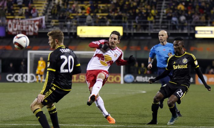 New York Red Bulls midfielder Sacha Kljestan (16), center, takes a shot between Columbus Crew midfielder Wil Trapp (20), left, and defender Harrison Afful (25) during the first leg of the MLS soccer Eastern Conference championship in Columbus, Ohio, Sunday, Nov. 22, 2015. The Crew won 2-0. (AP Photo/Paul Vernon)
