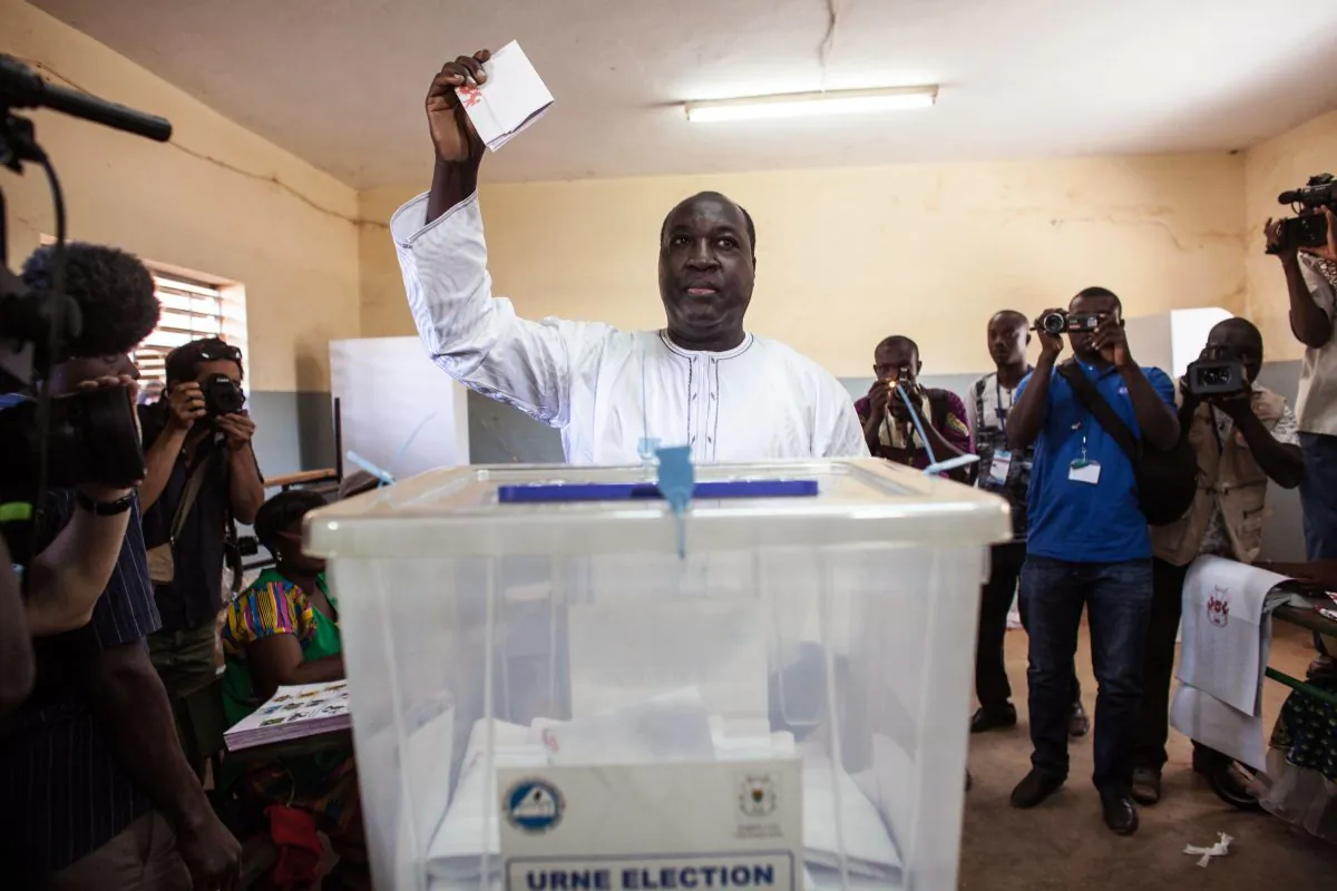 Burkina Faso presidential candidate from the UPC party Zephirin Diabre (C) holds up his ballot before he casts it during elections in Ouagadougou, Burkina Faso, Sunday, Nov. 29, 2015. (AP Photo/Theo Renaut)