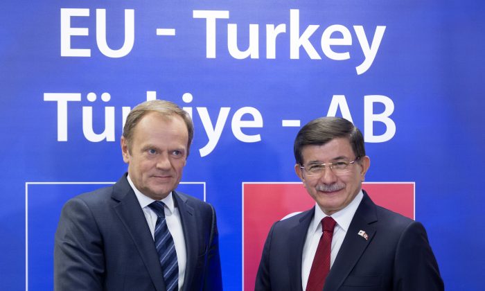 European Council President Donald Tusk, left, shakes hands with Turkish Prime Minister Ahmet Davutoglu during a meeting on the sidelines of an EU-Turkey summit at the EU Council building in Brussels on Sunday, Nov. 29, 2015. (Thierry Monasse, Pool Photo via AP)