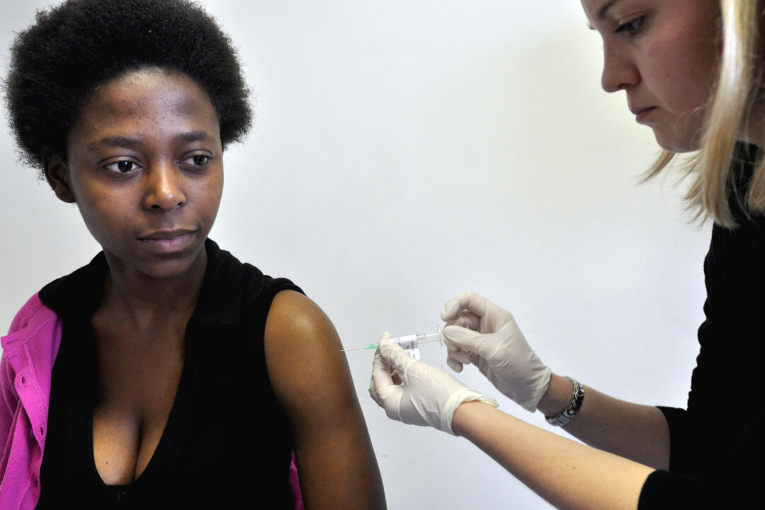 Dr. Camilla Samways (R) injects volunteer Nobathembu Mbembe the African-produced HIV vaccine at the iEmavundleni Center, in Crossroads, Cape Town, on July 28, 2009. South Africa launched human trials of the first African-produced HIV vaccine, as scientists seek new approaches to battling AIDS in the world's worst-affected country. The locally produced vaccine was tested in Soweto and Cape Town. (Rodger Bosch/AFP/Getty Images)