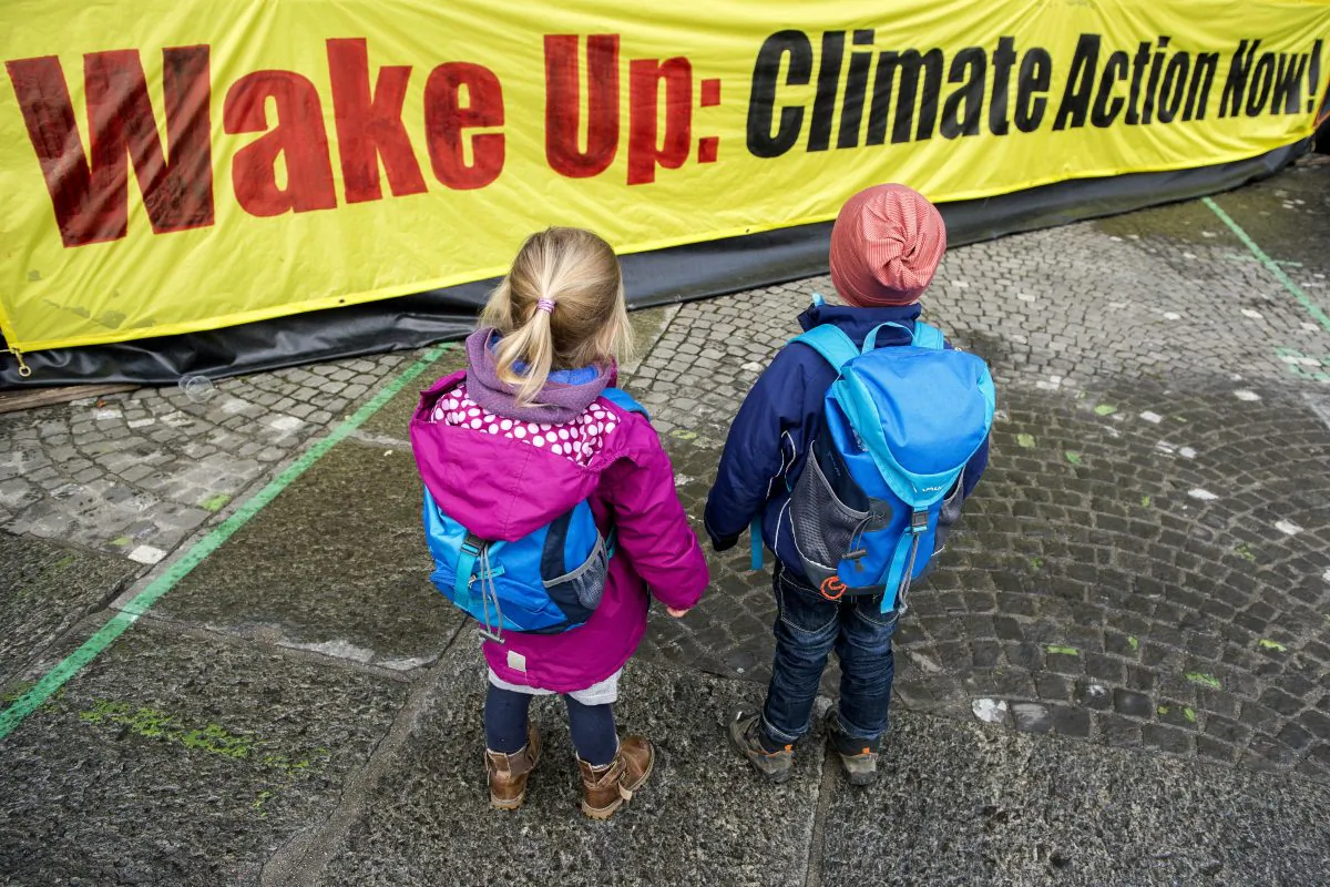 Two Children in front of a banner during a protest rally of the 'Climate Alliance Switzerland' in Zurich, Switzerland, on Nov. 28, 2015, ahead of the COP21 climate summit in Paris. (Anthony Anex/Keystone via AP)