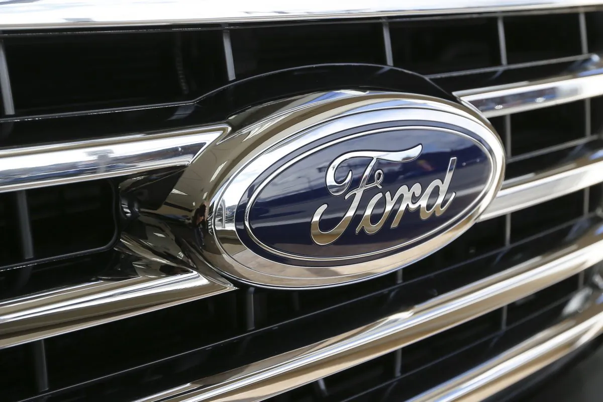 In this Thursday, Nov. 19, 2015, photo, the Ford blue oval badge is in the grill of a 2015 Ford F-150 XLT on display in the showroom at Butler County Ford in Butler, Pa. Ford said Monday, Nov. 30, 2015, it will book a $600 million fourth-quarter expense mainly for signing bonuses paid to union workers under a new four-year contract. (AP Photo/Keith Srakocic)